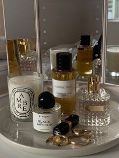 several different types of perfumes sitting on a plate in front of a large mirror