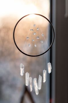 a wind chime with crystals hanging from it's center and sun shining through the window