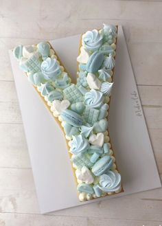 a letter made out of cookies on top of a white board with blue and green icing