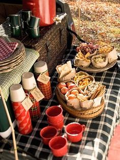 a picnic table filled with food and drinks on top of a checkered table cloth