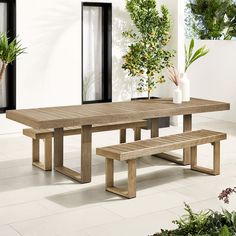 a wooden table with two benches in front of it and potted plants on the side