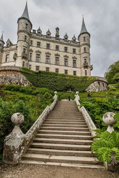 the stairs lead up to an old castle like building with turrets on top and green plants in front