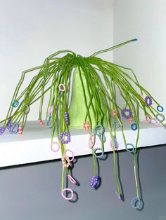 a green vase filled with lots of purple and pink beads on top of a shelf