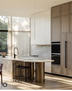 a kitchen with an island and stools next to the counter top in front of a window