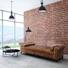 a living room with brick walls and leather couches in front of a large window