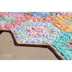 a colorful quilt is laying on the ground with it's center piece in the middle