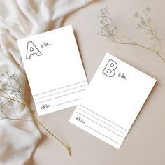 two white post - it notes sitting on top of a bed next to dried flowers