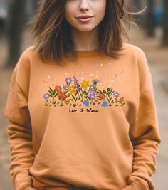 Feel the breeze with this colorful sweatshirt featuring flying petals and blooming flowers. The inscription 'Let it blow' adds a touch of whimsy. Perfect for those who love nature and vibrant designs, this sweatshirt is ideal for casual wear or cozy nights in during the fall and winter seasons. ABOUT THE PRODUCT ➤ Gildan 18000 sweatshirt made with a medium-heavy fabric blend of 50% cotton and 50% polyester (8.0 oz/yd² (271.25 g/m feels cozy and is the perfect choice for those colder months ➤ Made using 100% ethically grown US cotton ➤ Say goodbye to itchiness thanks to the gray, pearlized tear-away label SIZE ➤ Take a look at the photos to see a specific sizing chart for this sweatshirt ➤ Please note that these sweatshirts are unisex size meaning they are not women's fitted shirts. If you' Spring Crew Neck Sweatshirt With Plant Print, Spring Plants Print Long Sleeve Sweatshirt, Floral Print Spring Sweatshirt, Garden Clothing, Colorful Sweatshirt, Fitted Shirts, Gardening Outfit, Love Nature, Gifts For Nature Lovers