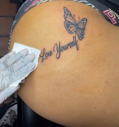 the back of a woman's stomach with a butterfly tattoo on her left side