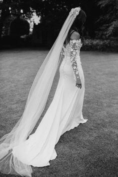 a woman in a wedding dress with a veil over her head and flowers on the shoulder