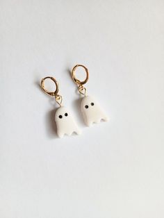 two white ghost earrings with black eyes and gold earwires on a white surface