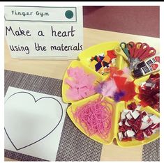 a heart shaped plate with scissors and other crafting supplies on it next to a sign that says make a heart using the materials