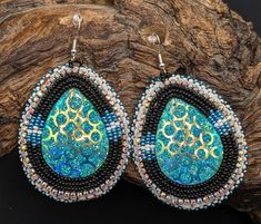 Beautifully hand beaded teardrop shaped 2 1/2-inch x 1 1/3-inch hook earrings. Sparkling resin center surrounded by rows of beautifully designed black, blue, and white beads.  Hypoallergenic hooks.  Real leather backing.  These come gift-ready in carboard Kraft jewelry box with descriptive card as shown. These amazing earrings were handcrafted for Creator's Place by Alisha Bloom, a Pine Point tribal artisan living on the White Earth Nation reservation in Northern Minnesota. Festival Teardrop Earrings With Ear Wire, Beaded Teardrop Earrings As Gift, Beaded Teardrop Earrings For Gift, Handmade Teardrop Earrings For Festival, Unique Handmade Teardrop Beaded Earrings, Artisan Teardrop Beaded Earrings As Gift, Artisan Teardrop Beaded Earrings For Gift, Festival Teardrop Beaded Earrings With Large Beads, Handmade Unique Teardrop Earrings