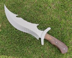 a knife that is laying on the ground in the grass with it's blade cut out