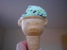 a hand holding an ice cream cone with blueberries on top