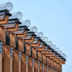 rows of solar panels on the side of a wooden building with blue sky in background