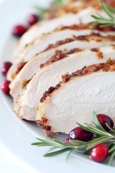 sliced turkey with cranberries and rosemary on the side sitting on a white plate