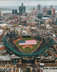 an aerial view of a baseball stadium with the american flag in the foreground and cityscape in the background