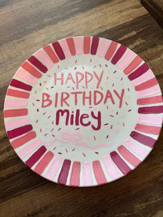 a pink and red plate with the words happy birthday miley written in frosting