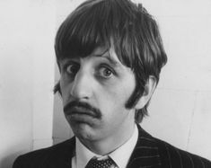 a black and white photo of a man in a suit with a moustache on his face