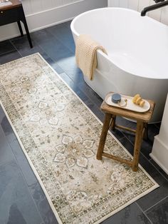 a bath tub sitting next to a rug on top of a wooden table in a bathroom