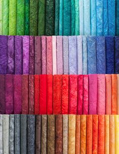 many different colored fabrics are arranged in rows