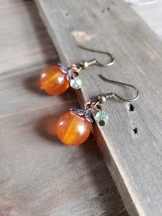 Fun and festive handmade resin pumpkin earrings with green crystal cut glass on rustic bronze metals. Delicate and detailed amber pumpkins with warm bronze stems and leaves. Cute addition to any outfit. Beautiful and sweet gift for a friend or loved one. Be sure to check out the HOLIDAY EARRINGS section at EarringsbyLCreations for all beautiful seasonal pieces available! https://www.etsy.com/shop/EarringsByLCreations?section_id=25034194 Made with quality materials and always nickel and lead free Handmade Orange Earrings For Everyday, Handmade Orange Everyday Earrings, Wire Wrapped Pumpkin Earrings, Whimsical Handmade Orange Earrings, Orange Nickel-free Earrings For Halloween, Resin Pumpkin, Fall Bead, Holiday Earrings, Earrings Wire