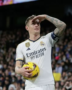 a man holding a soccer ball in his right hand and saluting to the crowd