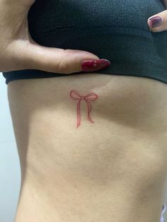 a woman's stomach with a red bow tattoo on it