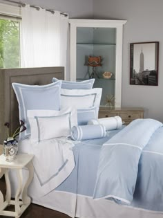 a blue and white bed in a bedroom next to a night stand with a clock on it