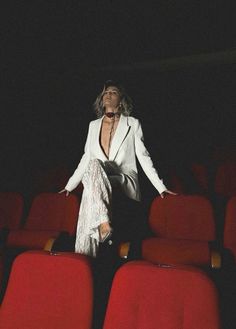 a woman standing in the middle of a row of red seats with her arms outstretched