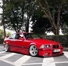 a red car parked in front of some trees