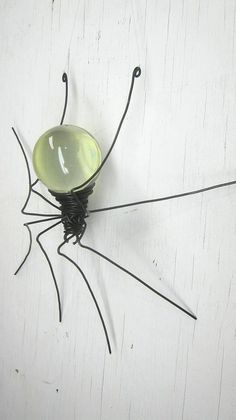 a metal spider sculpture sitting on top of a white wall