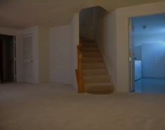 an empty living room with stairs leading up to the door