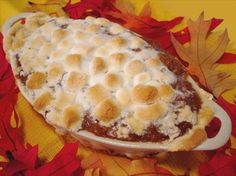 a casserole dish with meat and cheese on it, surrounded by fall leaves