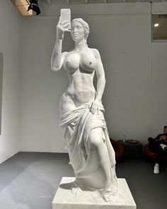 a white statue with a cell phone in it's hand