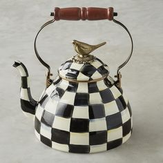 a black and white checkered tea kettle with a bird on top