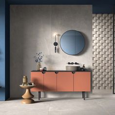 a bathroom with two sinks and a round mirror on the wall next to an orange cabinet