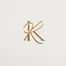 the letter k is inscribed in gold on a white paper with a black and brown design