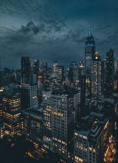 the city skyline is lit up at night with skyscrapers in the foreground and clouds in the background