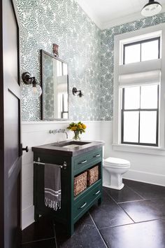 a bathroom with a sink, mirror and toilet in it's corner area next to a window