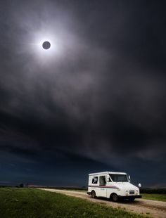 a food truck driving down a dirt road under a dark sky with the moon in the distance