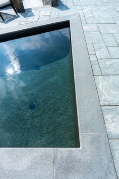 an empty swimming pool with blue sky and clouds reflected in it's water surface