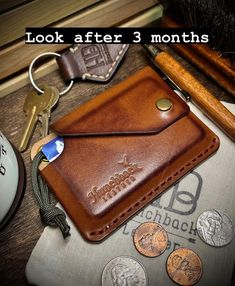 a brown leather wallet sitting on top of a table next to coins and a pen