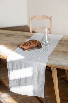 a wooden table with a bottle and glass on it next to a piece of bread