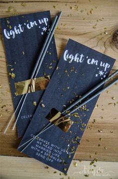 three black and gold candles on top of a wooden table with confetti scattered around them