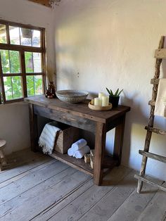 a wooden table with candles and towels on it next to a window in a room