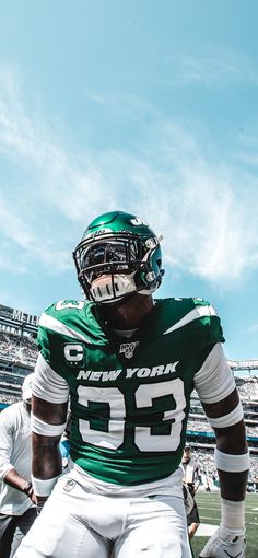 a football player sitting on the sidelines at a game wearing a green and white uniform