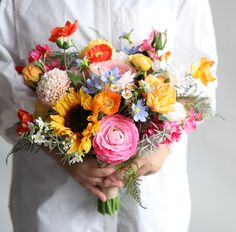 a person holding a bouquet of flowers in their hands and wearing a white shirt behind them