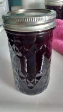 a jar filled with jam sitting on top of a counter next to a pink towel